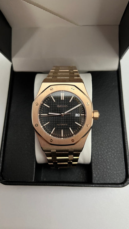 Royal Oak (Rose Gold) Seiko NH35 automatic mod watch. A front view shows the rose gold watch with a black dial centered inside an open black display box.