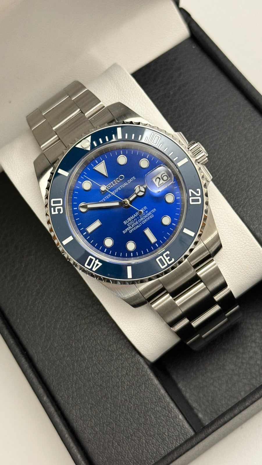 Submariner (Blue) Seiko NH35 automatic mod watch. A high angle shot of a blue dial and blue bezel watch with a silver metal link bracelet in a box.
