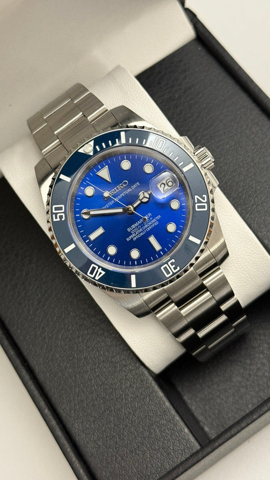 Submariner (Blue) Seiko NH35 automatic mod watch. A high angle shot of a blue dial and blue bezel watch with a silver metal link bracelet in a box.