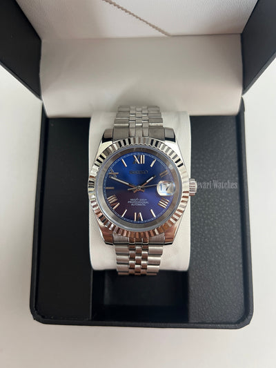 Datejust (Royal Blue Roman) Seiko NH35 automatic mod watch. A blue dial watch with a silver fluted bezel and jubilee bracelet shown in a box from a front view.