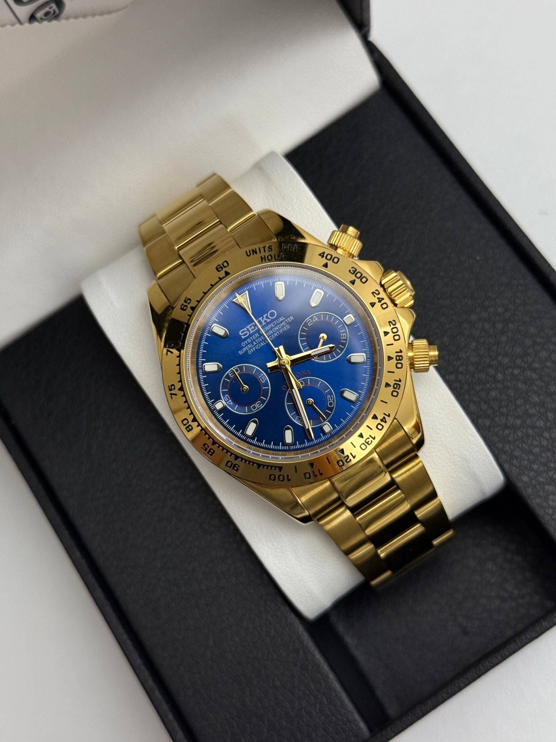 Daytona (Blue Gold) Seiko VK63 meca-quartz chronograph mod watch. A gold tone chronograph watch with a blue dial and gold bezel sits in a box in a high angle full shot.