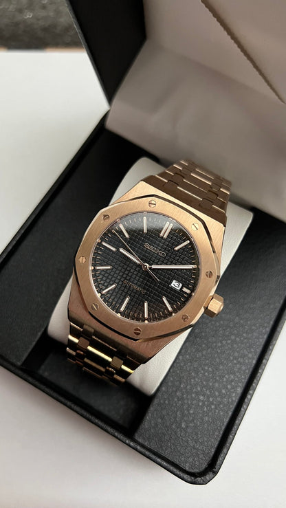 Royal Oak (Rose Gold) Seiko NH35 automatic mod watch. A slightly angled view shows the rose gold watch with a black dial inside an open black display box.