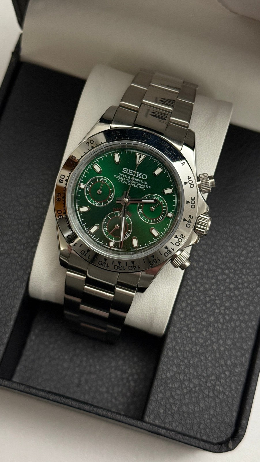Daytona (Green) Seiko VK63 meca-quartz chronograph mod watch. A green dial watch with a silver bezel and metal link bracelet inside an open black display box.