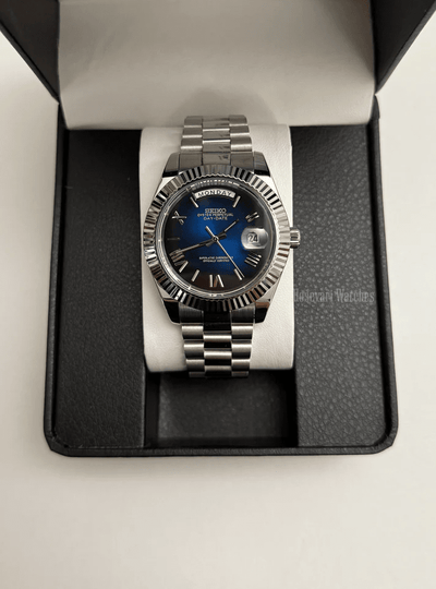 Day-Date (Blue Roman) Japanese automatic mod watch. A watch in a box with a blue dial and silver fluted bezel on a silver metal bracelet.