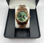 Day-Date (Rose Gold, Green) Japanese automatic mod watch. A full watch shot shows the rose gold watch with a green dial resting on a white pillow inside a box.