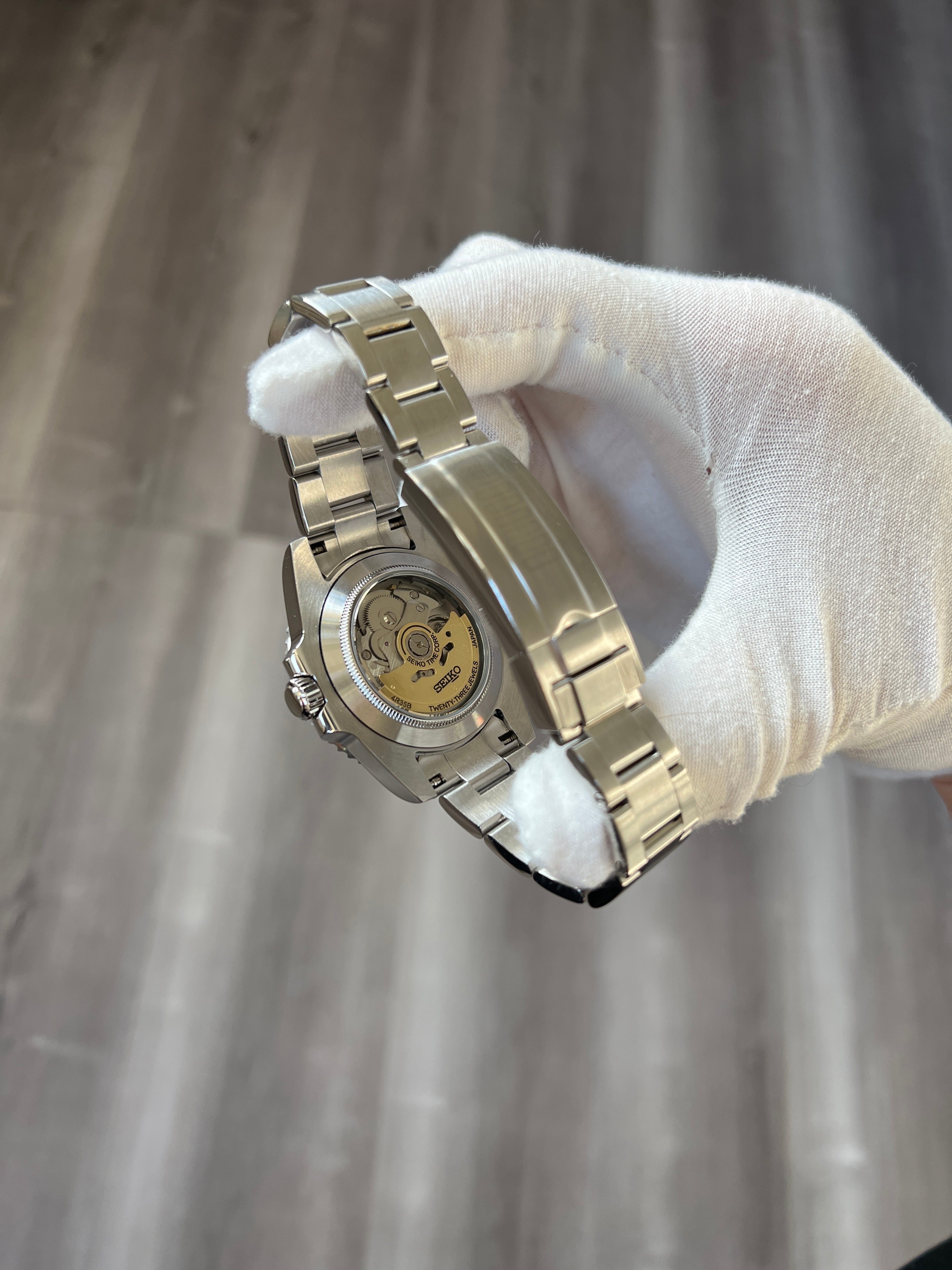 Submariner (Black) Seiko NH35 automatic mod watch. A caseback detail showing the mechanical movement of the watch held by a gloved hand.