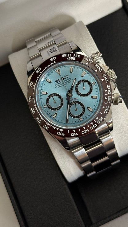 Daytona (Ice Blue) Seiko VK63 meca-quartz chronograph mod watch. A high angle full watch shot featuring a light blue dial and brown bezel on a silver metal bracelet.