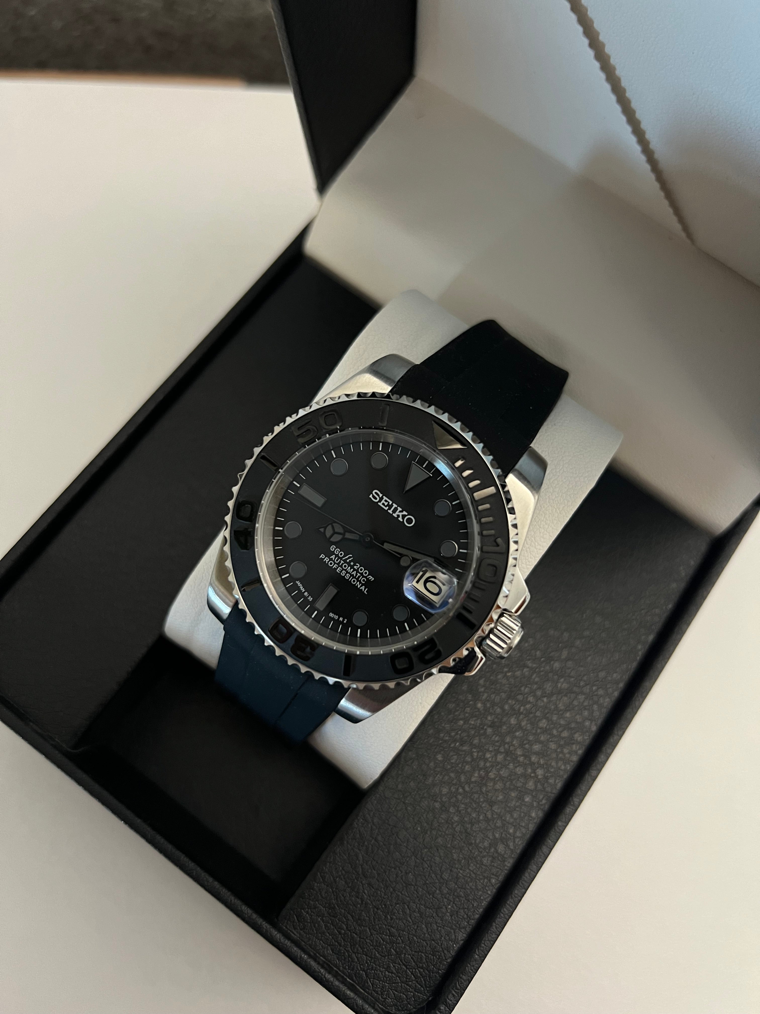 Yacht-Master (Grey) Seiko NH35 automatic mod watch. A full watch with a black dial and bezel on a black rubber strap inside a watch box.