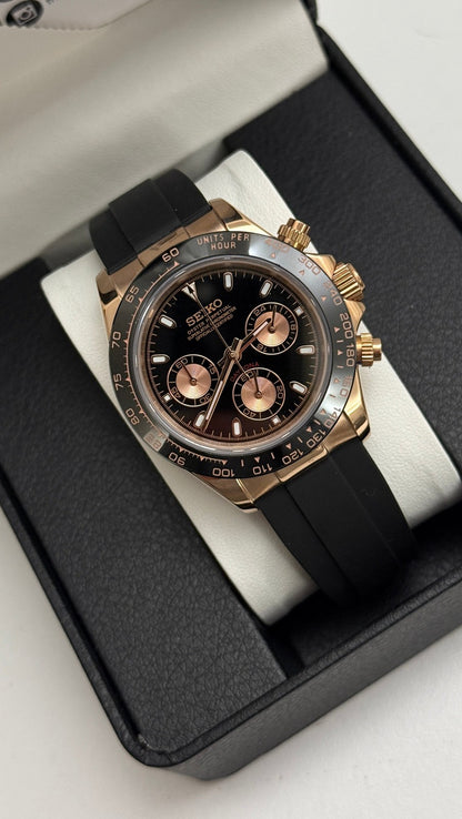 Daytona (Black & Rose Gold) Seiko VK63 meca-quartz chronograph mod watch. A black dial watch with a black bezel and black rubber strap shown in a box packaging shot.