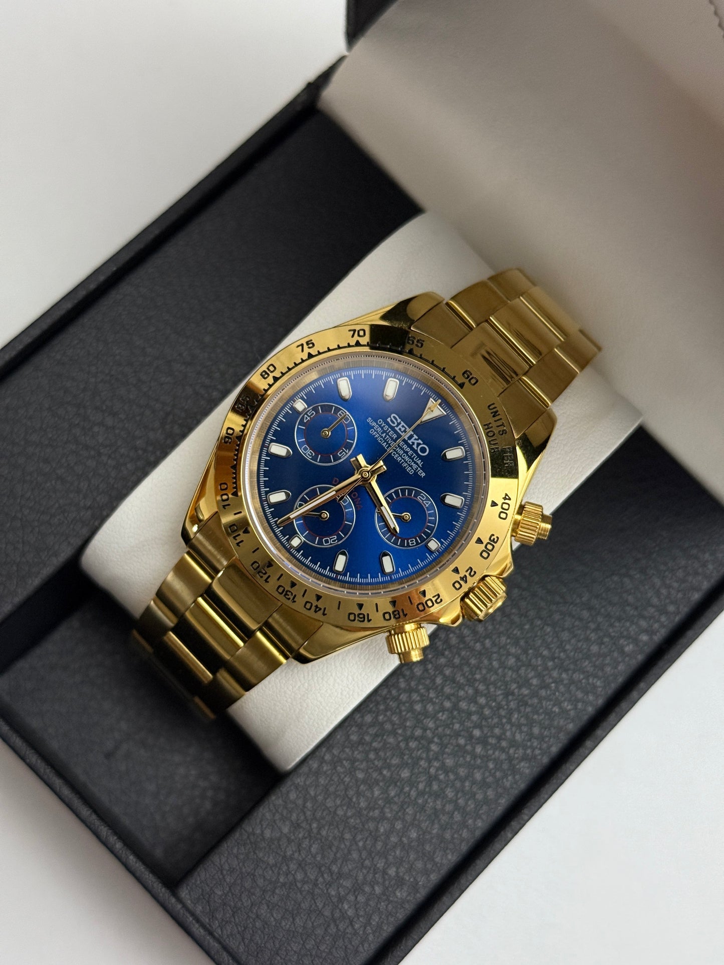 Daytona (Blue Gold) Seiko VK63 meca-quartz chronograph mod watch. A gold tone chronograph watch with a blue dial and gold bezel is shown in a high angle full shot.