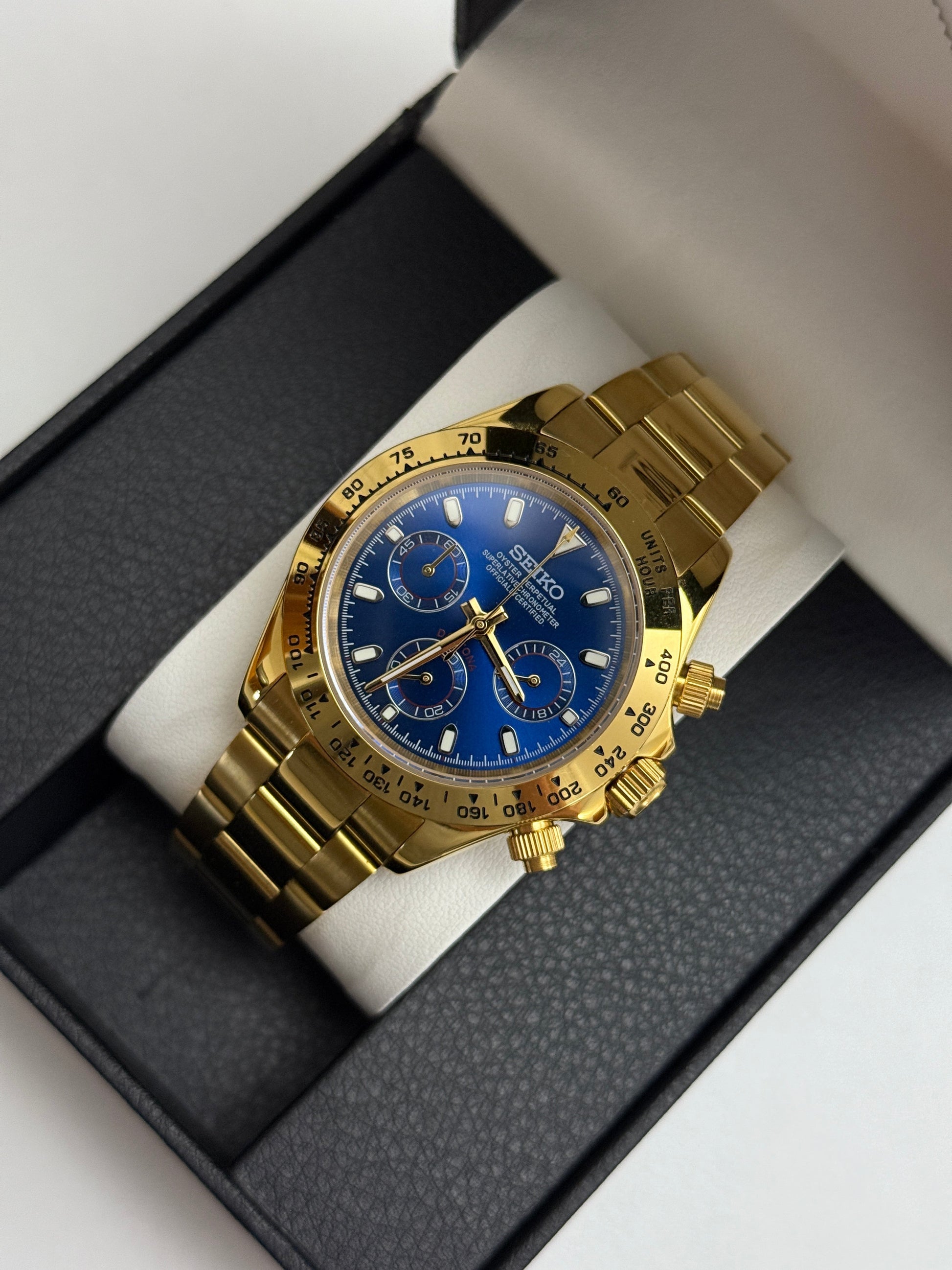 Daytona (Blue Gold) Seiko VK63 meca-quartz chronograph mod watch. A gold tone chronograph watch with a blue dial and gold bezel is shown in a high angle full shot.