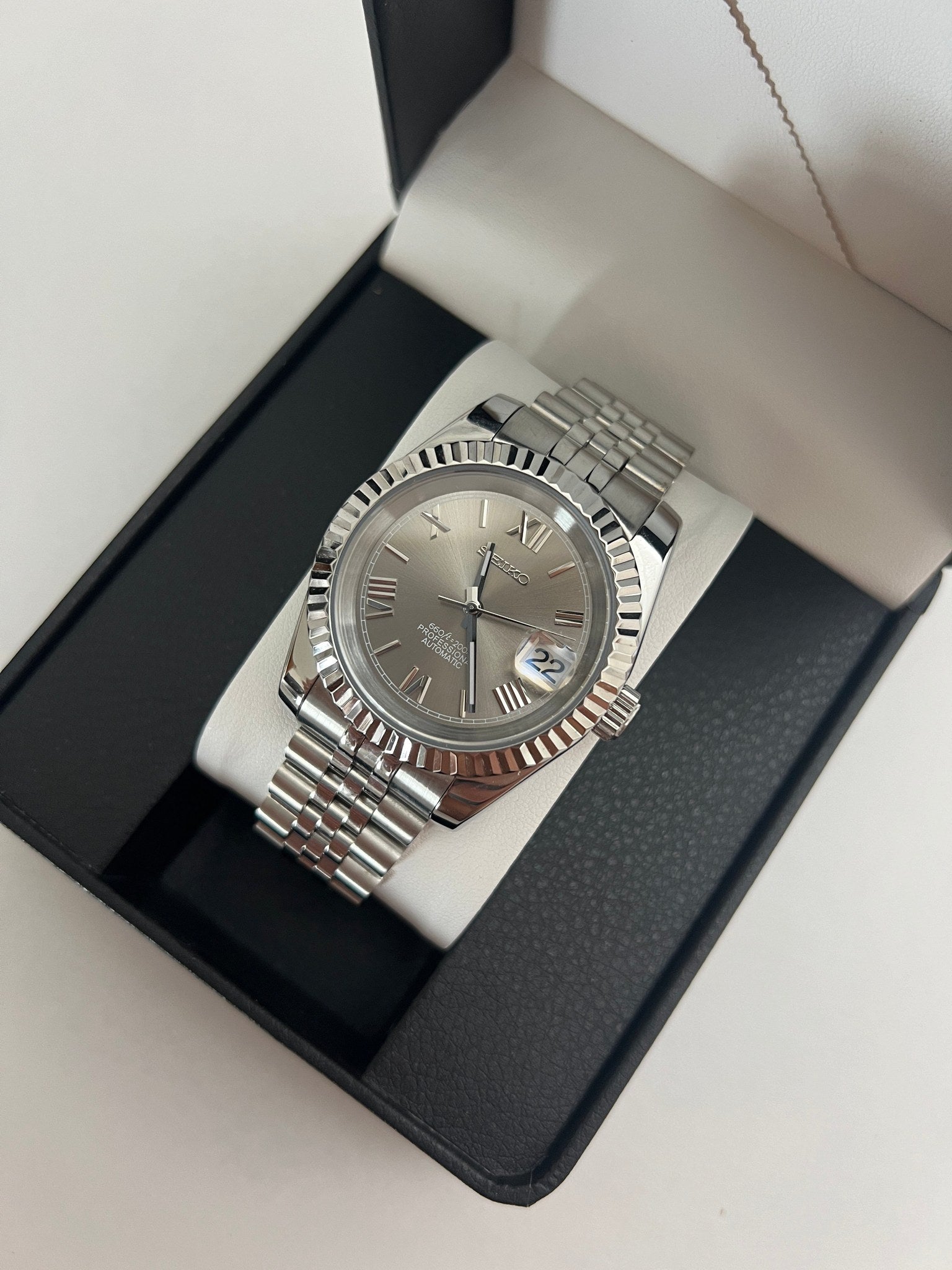 Datejust (Grey Roman) Seiko NH35 automatic mod watch. A grey dial watch with a silver fluted bezel and a metal jubilee bracelet inside an open watch box.