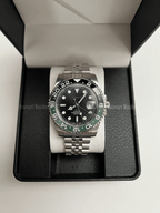 GMT (Sprite) Seiko NH34 GMT automatic mod watch. A full watch with a black dial and a black bezel on a jubilee bracelet inside a watch box.