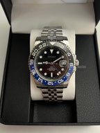 GMT (Batman) Seiko NH34 GMT automatic mod watch. A front view of the watch in a box featuring a black dial and blue and black bezel on a silver bracelet.