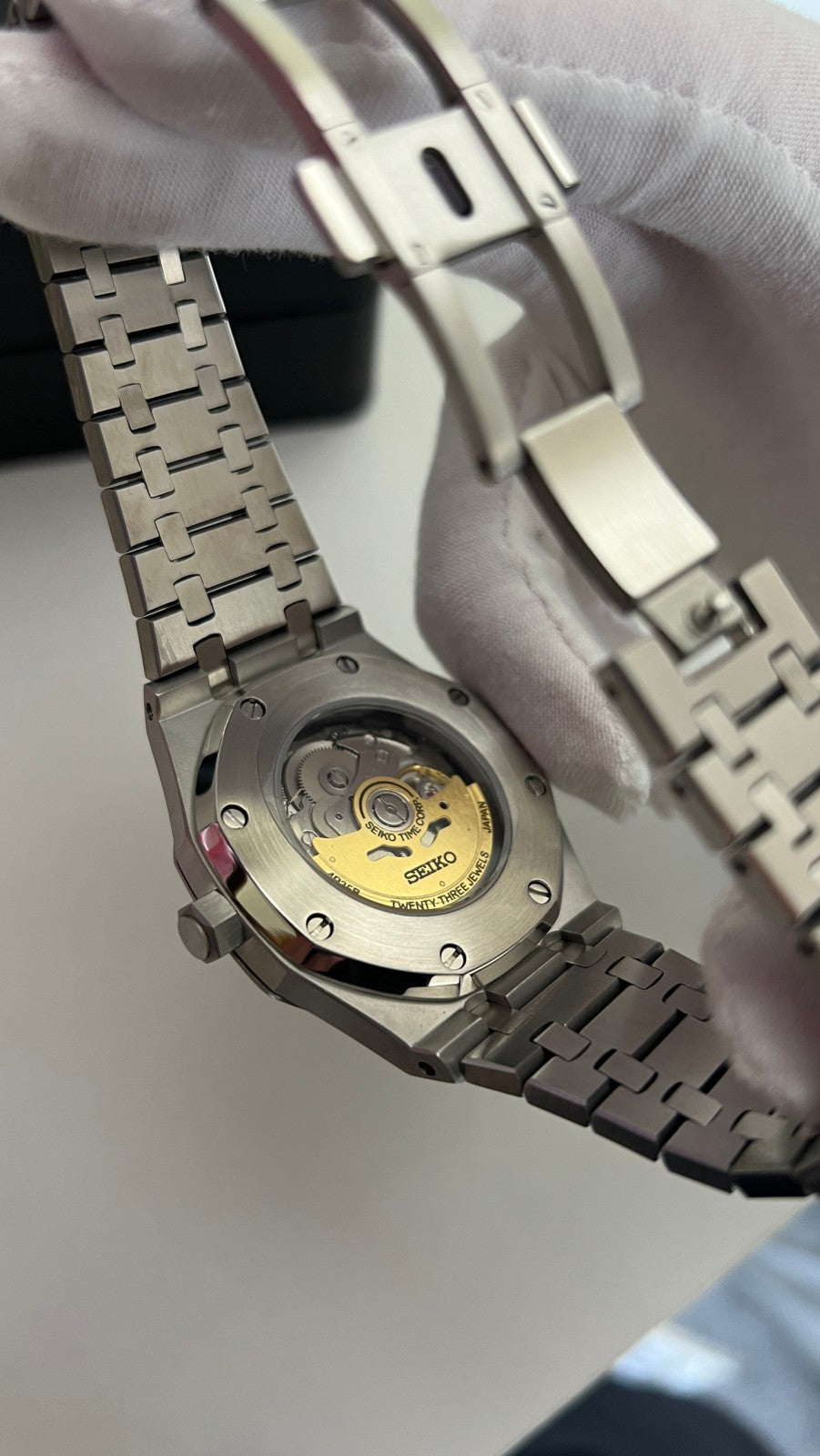 Royal Oak (Skeleton) Seiko NH70 skeleton automatic mod watch. A caseback detail shot shows the mechanical movement and the silver metal link bracelet.