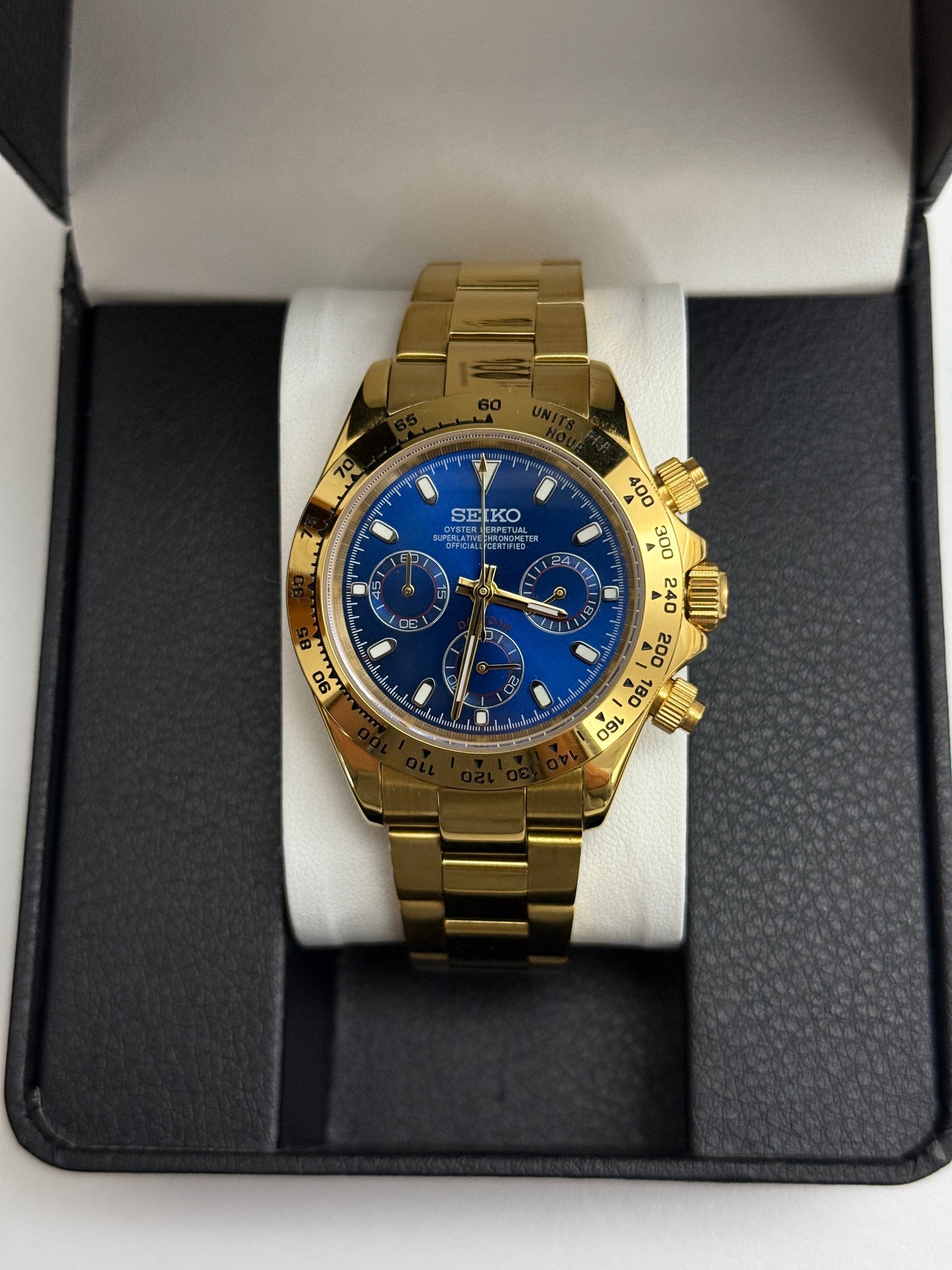 Daytona (Blue Gold) Seiko VK63 meca-quartz chronograph mod watch. A gold tone chronograph watch with a blue dial and gold bezel is shown in a straight on full shot.