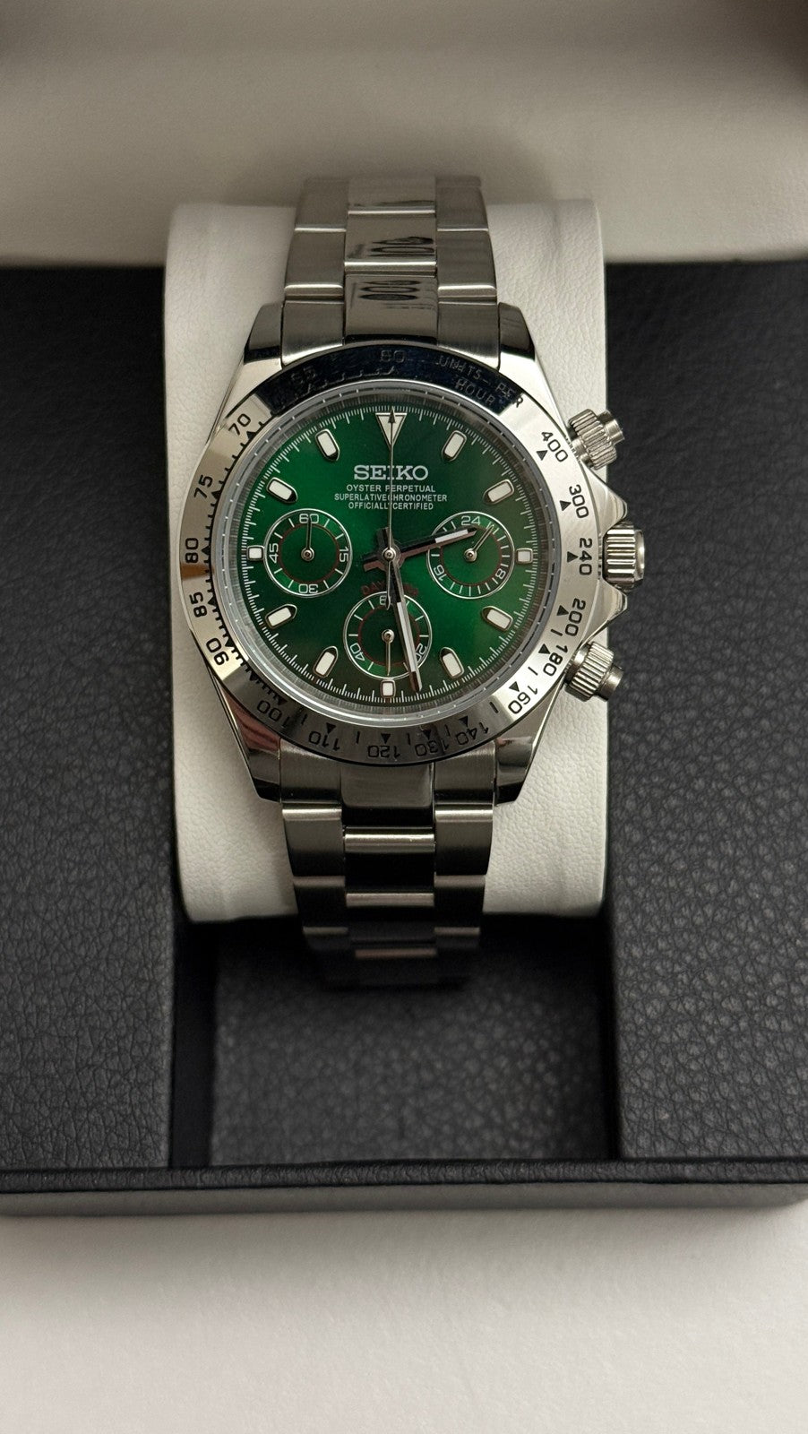 Daytona (Green) Seiko VK63 meca-quartz chronograph mod watch. A green dial watch with a silver bezel and metal link bracelet inside an open black display box.