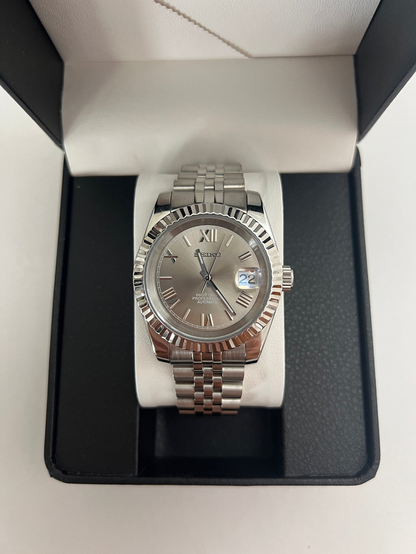 Datejust (Grey Roman) Seiko NH35 automatic mod watch. A grey dial watch with a silver fluted bezel and a metal jubilee bracelet inside an open watch box.
