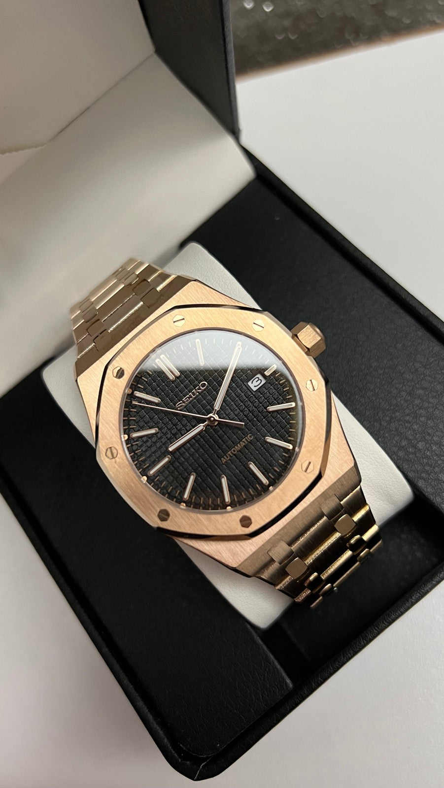 Royal Oak (Rose Gold) Seiko NH35 automatic mod watch. A high angle shot shows the rose gold watch with a black dial resting inside an open black display box.