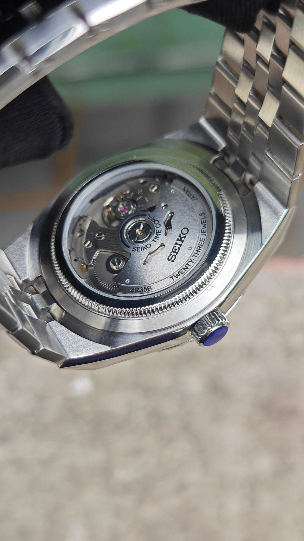 Land-Dweller (Tiffany) Seiko NH35 automatic mod watch. The silver caseback of a watch showing the internal mechanical movement and a clear exhibition window.