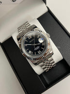Datejust (Black Roman) Seiko NH35 automatic mod watch. A black dial watch with a silver fluted bezel and jubilee bracelet inside a box in a high angle shot.