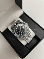 GMT (Sprite) Seiko NH34 GMT automatic mod watch. A full watch with a black dial and a black bezel on a jubilee bracelet inside a watch box.