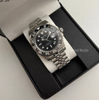 GMT (Bruce Wayne) Seiko NH34 GMT automatic mod watch. A full watch shot of a black dial watch with a black bezel inside a black presentation box.