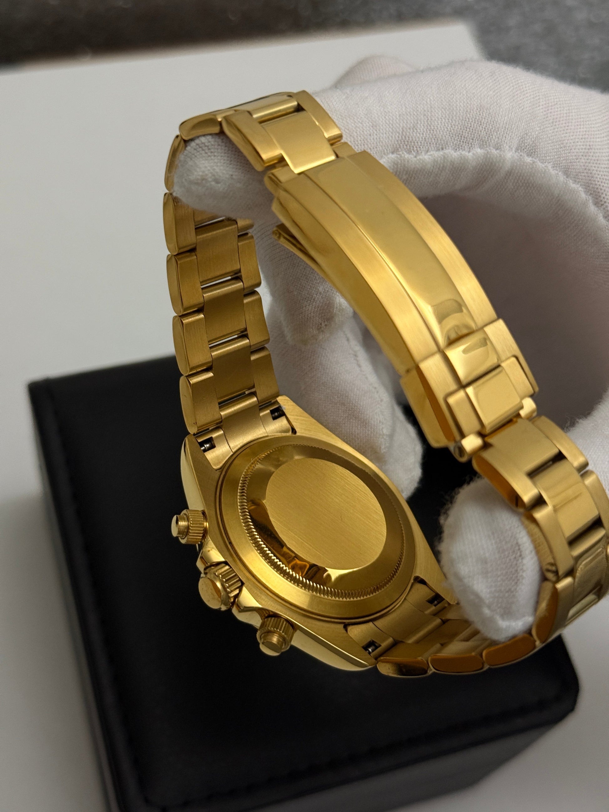 Daytona (Blue Gold) Seiko VK63 meca-quartz chronograph mod watch. A white gloved hand holds the back of a gold tone watch showing the caseback and bracelet in a close up shot.