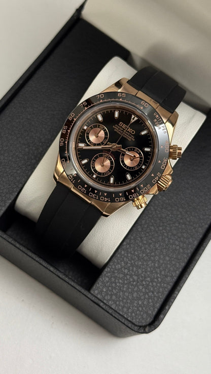 Daytona (Black & Rose Gold) Seiko VK63 meca-quartz chronograph mod watch. A black dial watch with a black bezel and black rubber strap shown in a high angle box shot.