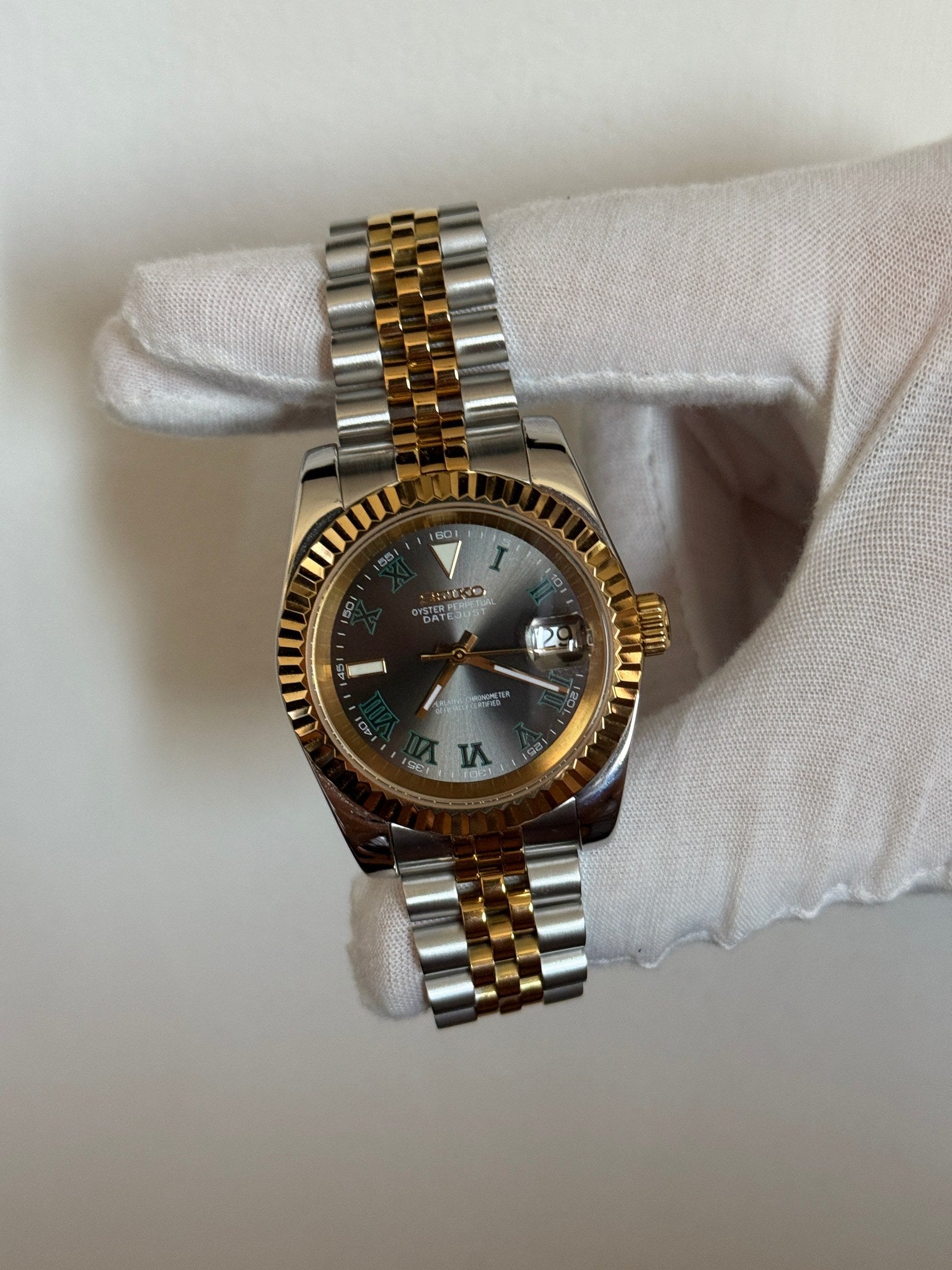 Datejust (Wimbledon Two-Tone) Seiko NH35 automatic mod watch. A hand in a white glove holds the watch showing the dark grey dial and gold fluted bezel on a two tone bracelet.