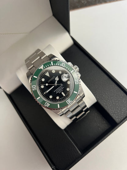 Submariner (Kermit) Seiko NH35 automatic mod watch. A full watch with a black dial and green bezel on a metal link bracelet inside an open watch box.