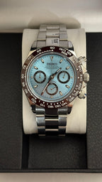 Daytona (Ice Blue) Seiko VK63 meca-quartz chronograph mod watch. A centered full watch shot displaying a light blue dial and brown bezel on a silver metal bracelet.