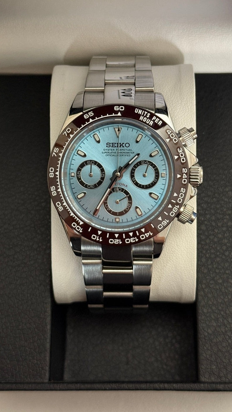 Daytona (Ice Blue) Seiko VK63 meca-quartz chronograph mod watch. A centered full watch shot displaying a light blue dial and brown bezel on a silver metal bracelet.
