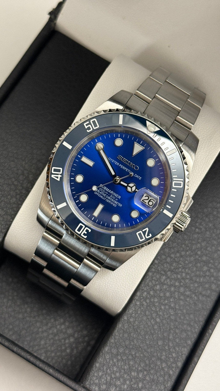 Submariner (Blue) Seiko NH35 automatic mod watch. A slightly angled view of a blue dial and blue bezel watch with a silver metal link bracelet in a box.