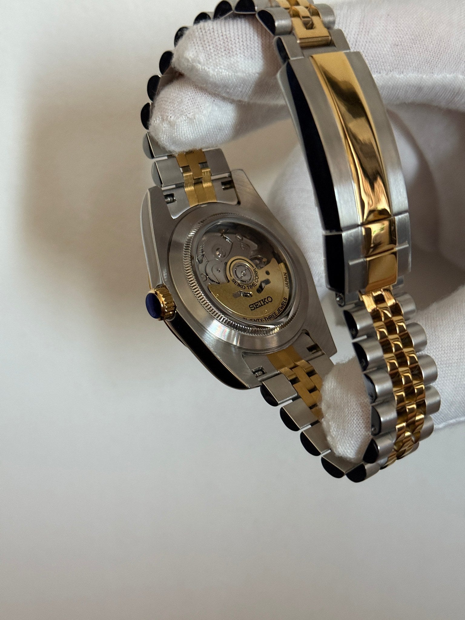 Datejust (Wimbledon Two-Tone) Seiko NH35 automatic mod watch. A hand in a white glove shows the caseback detail of the watch revealing the mechanical movement inside.