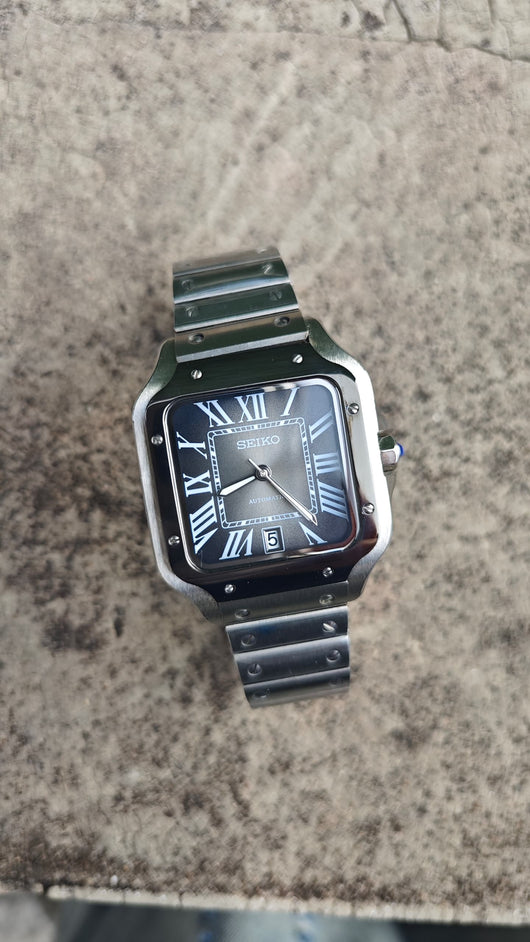 Santos (Graphite) Seiko NH35 automatic mod watch. A top down full watch shot showing a grey dial with a black bezel and a metal link bracelet.