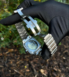 Santos (Emerald Green) Seiko NH35 automatic mod watch. A caseback detail shot showing the mechanical movement and the metal bracelet held by a gloved hand.